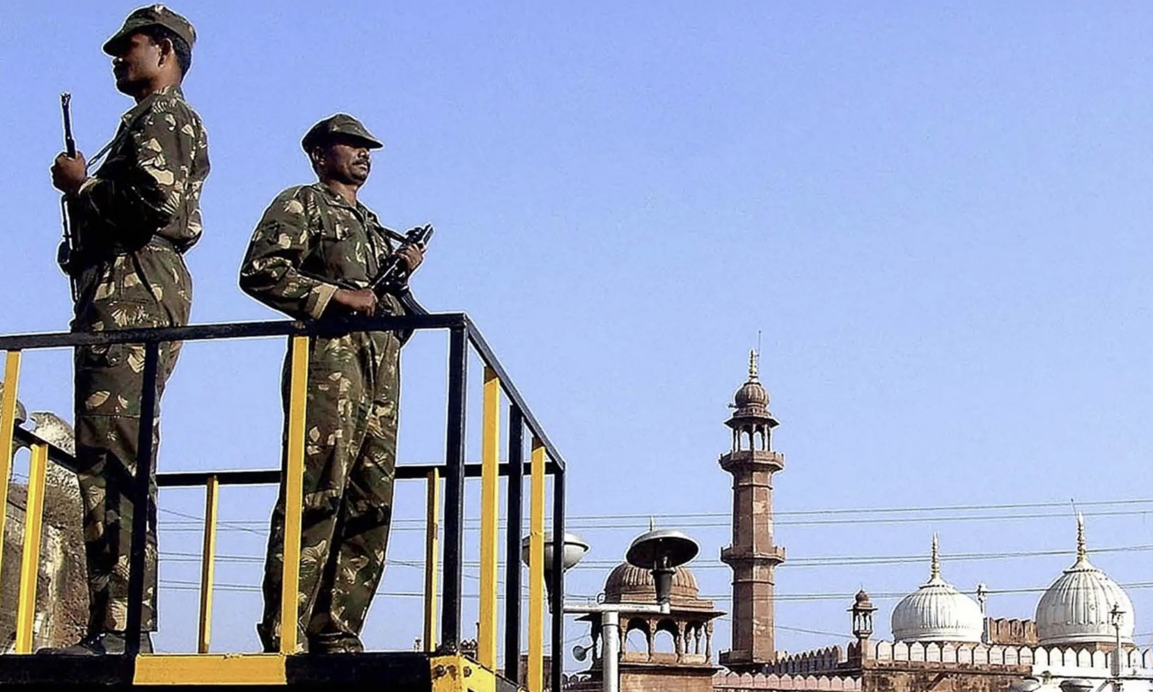 Two soldiers standing on a platform overlooking a mosque